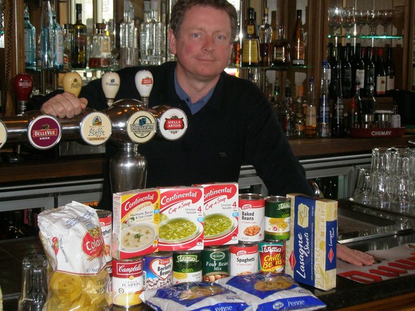 Belgian beer caf&#233; owner Brian Collins shows some of the food parcels already donated to the Auckland City Mission fundraising initiative and being collected at the five venues across the city. 